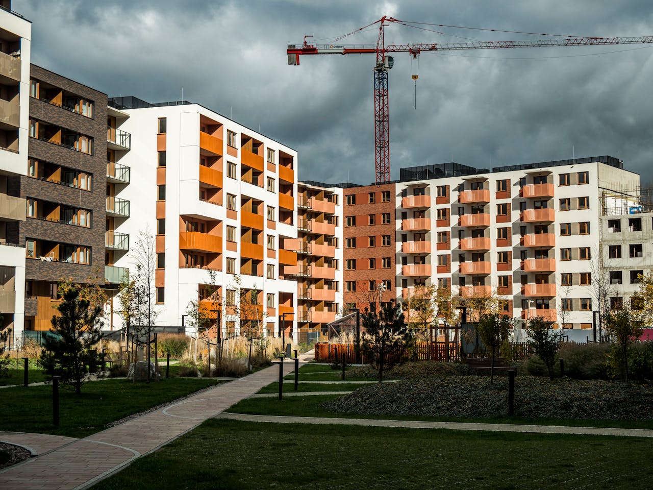 footer-cta-img Newly built residential buildings under cloudy skies with a construction crane.